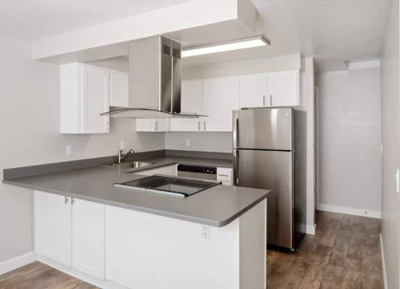 A modern kitchen with white cabinets and stainless steel appliances.