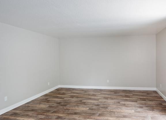 A room with wooden flooring and white walls.