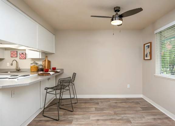 A kitchen with a white counter and a fan on the ceiling.