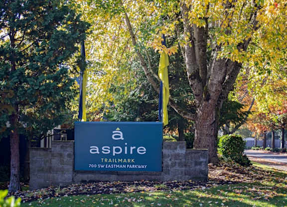 A sign for Aspire Trailmark is shown in front of a tree.