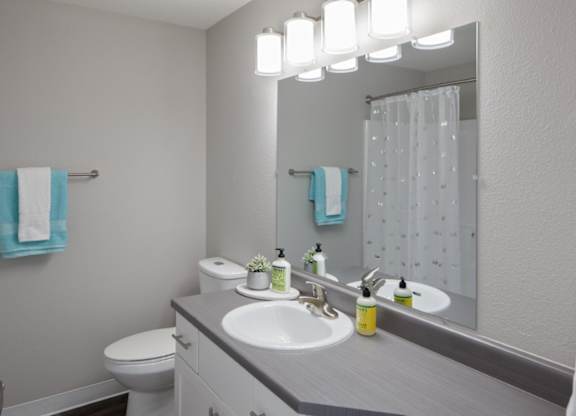 A bathroom with a white toilet, sink, and mirror.