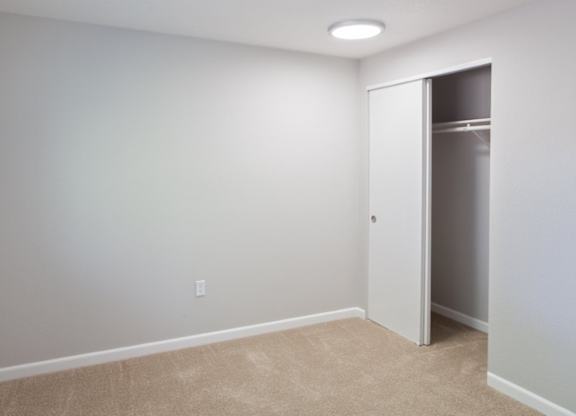 A room with a white door and a carpeted floor.
