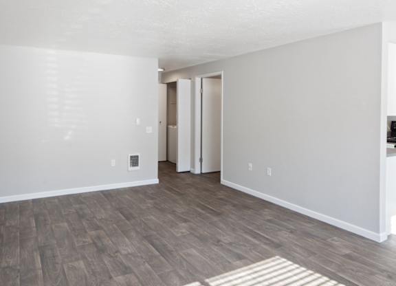 A room with a wooden floor and a white wall with a door.