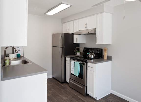 A kitchen with a black refrigerator and stove top oven.