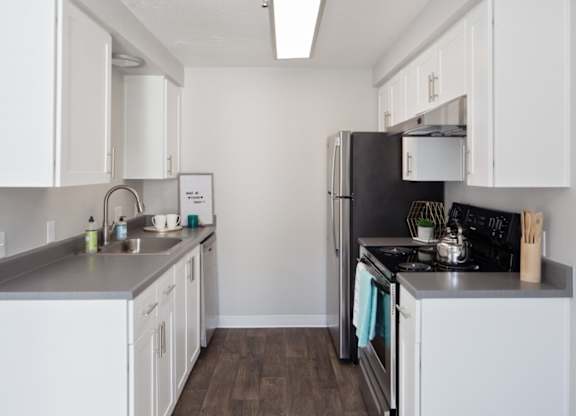 A kitchen with white cabinets and a black refrigerator.