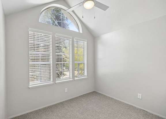 A room with a window covered by white blinds and a ceiling fan.