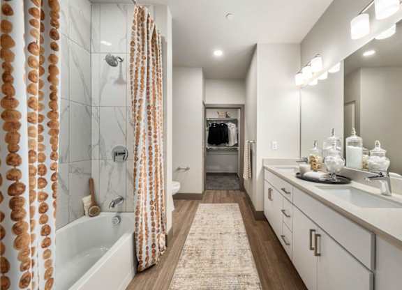 A bathroom with a white tub, sink, and shower curtain.