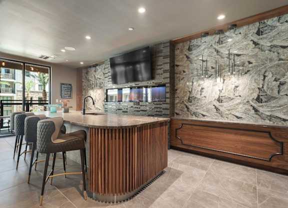 A bar area with a stone wall and wooden chairs.