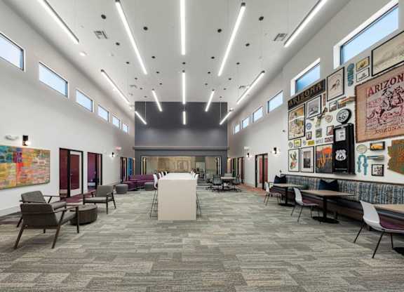 A modern office space with a long carpeted hallway and a variety of seating options.