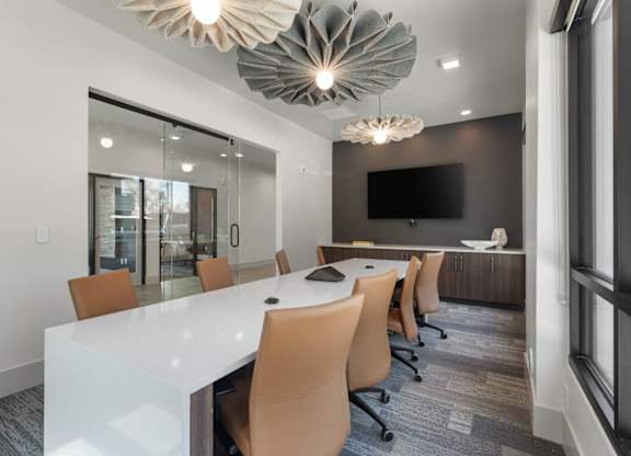 A conference room with a long white table and orange chairs.