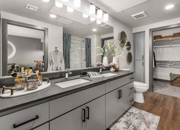 A bathroom with a large mirror, a sink, and a toilet.