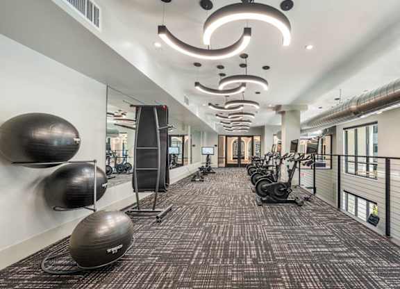 A gym with a variety of equipment including treadmills, weights, and exercise balls.