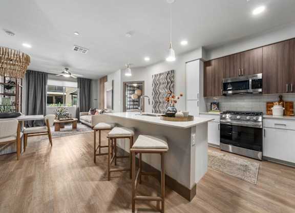 A modern kitchen with wooden floors and a central island.