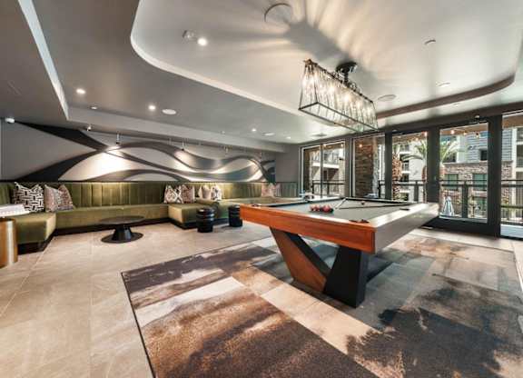 A room with a pool table and a green couch.