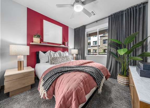 A bedroom with a bed, nightstand, and a ceiling fan.