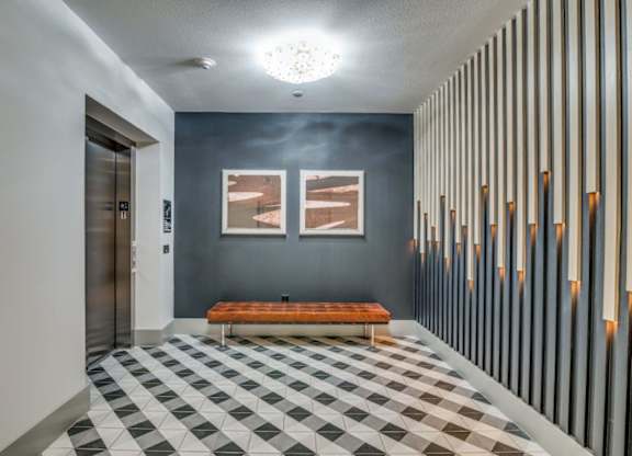 A hallway with a bench and a checkered floor.