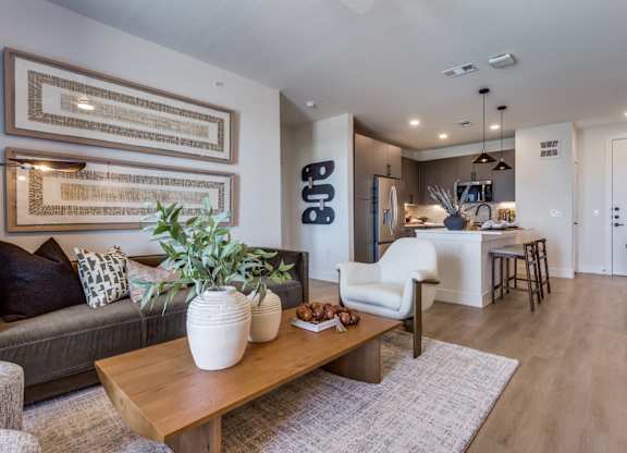 A living room with a grey couch, a wooden coffee table, and a large framed artwork on the wall.