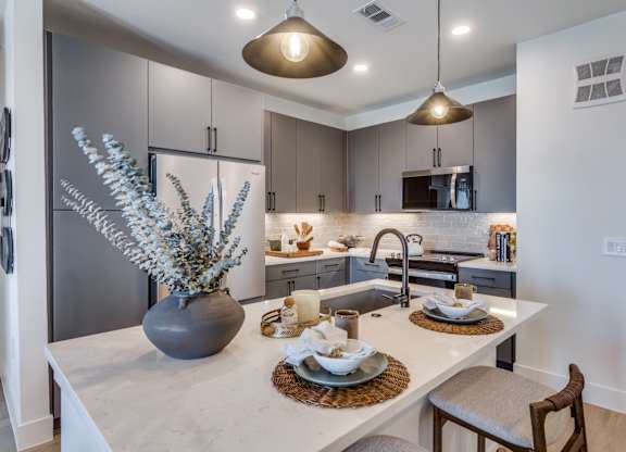 A modern kitchen with a marble countertop and a dining table set for two.