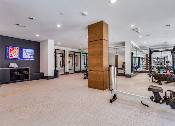 A gym with a variety of equipment including a treadmill, weights, and a television.