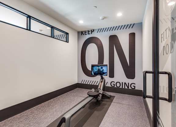 A treadmill is in a room with a wall that says "Keep On Going".