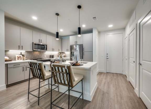 A kitchen with a white counter and brown chairs.