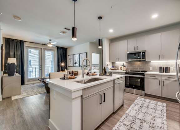 A modern kitchen with white cabinets and stainless steel appliances.