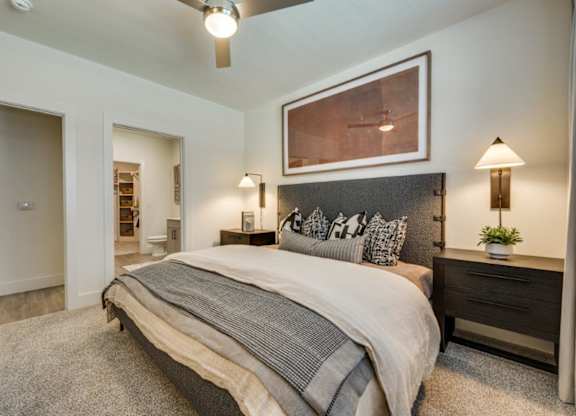 A bedroom with a large bed and a painting above it.