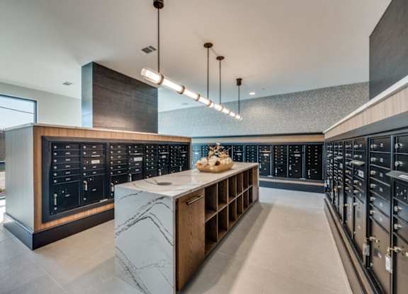 A modern kitchen with a marble island and dark cabinets.