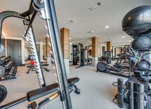A gym with a variety of equipment including treadmills, weights, and exercise balls.