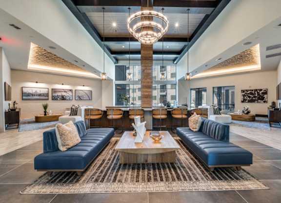 A large, modern living room with a long blue couch and a wooden coffee table.