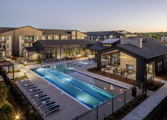 an aerial view of a swimming pool at night with apartments in the background
