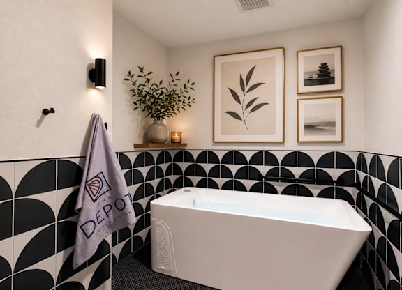 A bathroom with a black and white tiled wall and a white bathtub.
