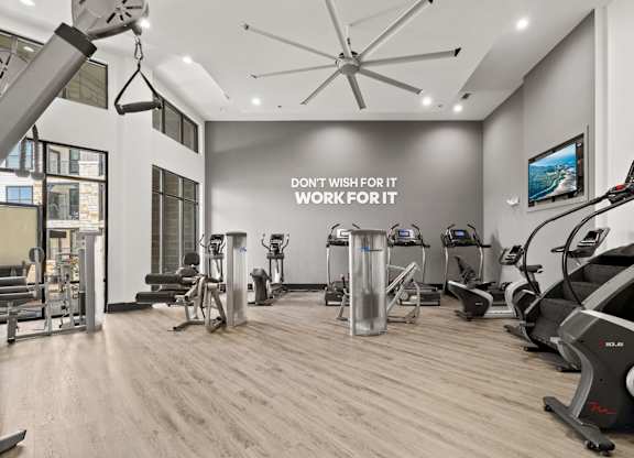A gym with a variety of equipment and a motivational sign on the wall.