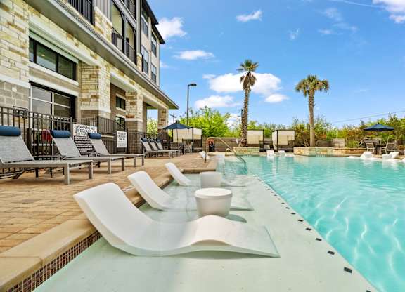 A pool with a white bench and a building behind it.