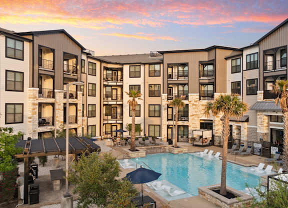 A large apartment complex with a pool in the foreground.