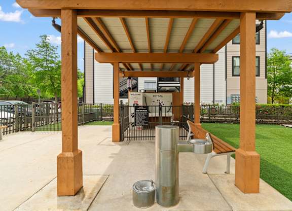 A wooden pergola with a metal pole and a bench underneath it.