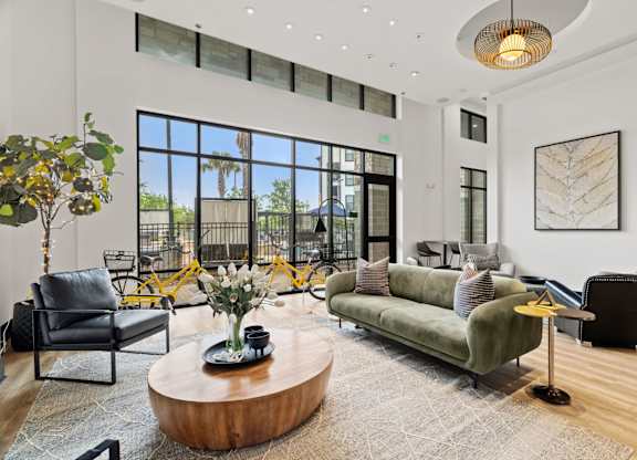 A living room with a green couch, a coffee table, and a large window.
