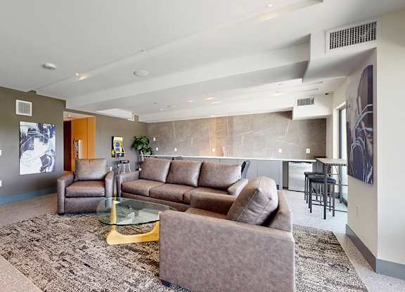 A living room with a brown couch and a glass coffee table.