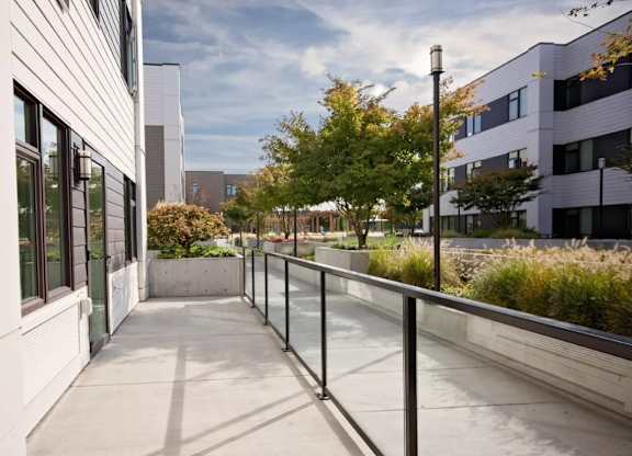 A long, narrow walkway with a metal railing separates two buildings.