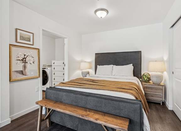 A bedroom with a bed, nightstand, and a painting on the wall.