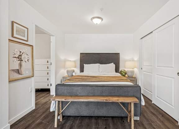 A bedroom with a bed, nightstands, and a bench.