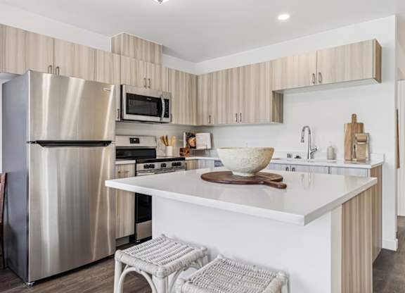 A modern kitchen with a stainless steel refrigerator and a white countertop.