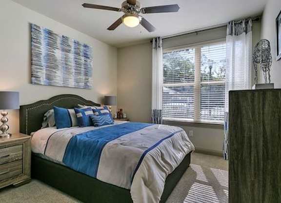 A bedroom with a bed, nightstand, and a ceiling fan.