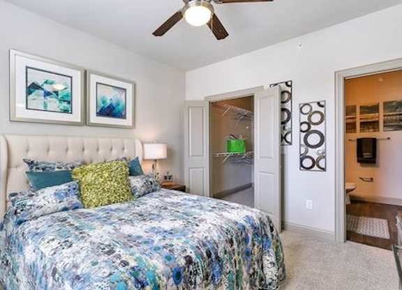 A bedroom with a large bed and a ceiling fan.