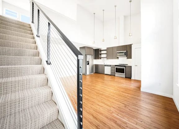 A staircase with a metal railing leads to a kitchen area.