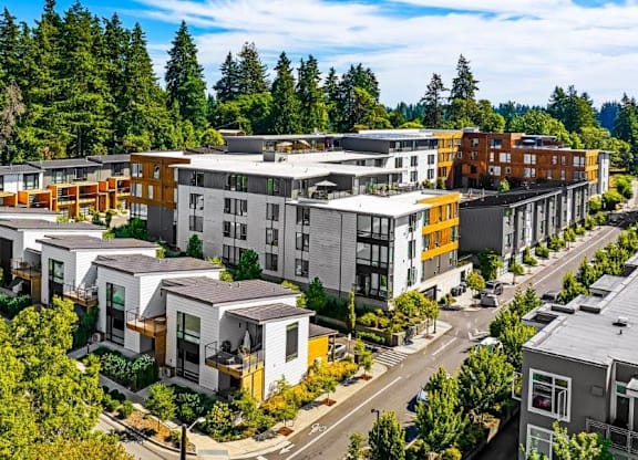 A modern apartment complex with multiple buildings and a parking lot in front.