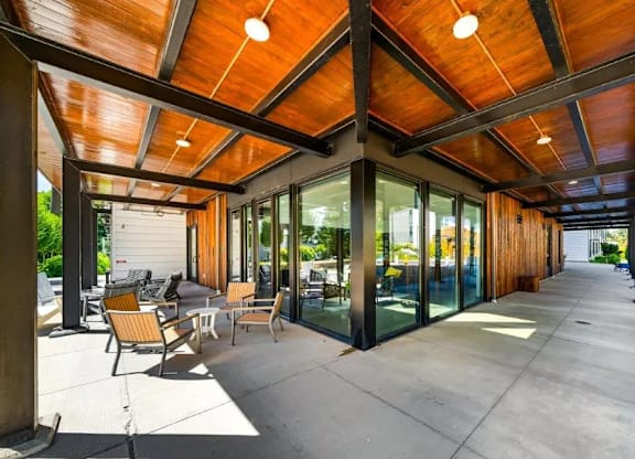 A wooden covered patio with chairs and tables.
