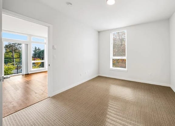 A room with a carpeted floor and a window with blinds.