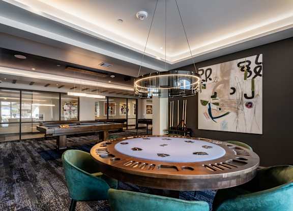 A poker table is surrounded by chairs in a room with a large painting on the wall.
