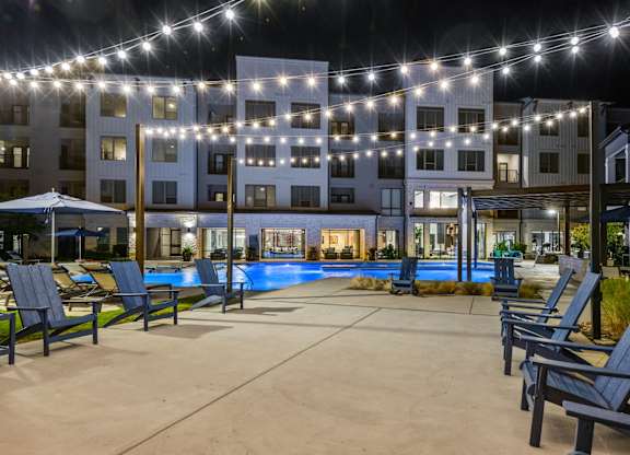 A pool area with lounge chairs and a building in the background.